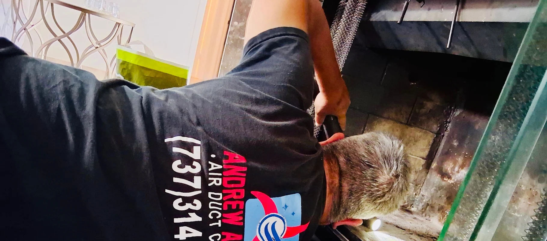 Technician sweeping a chimney flue with a vacuum running to keep soot out of the room