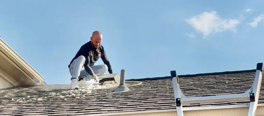 Technician clearing a dryer vent at the roof cap on a Central Texas home