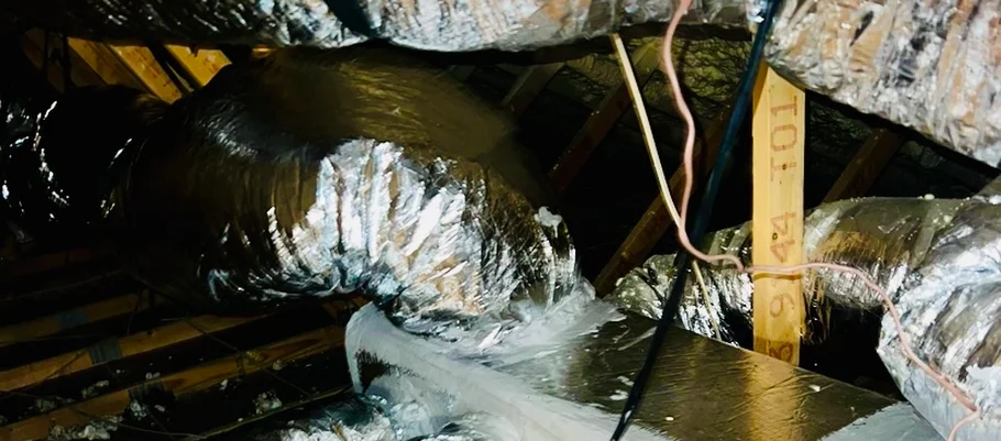 Newly installed insulated flex duct running through a Central Texas attic